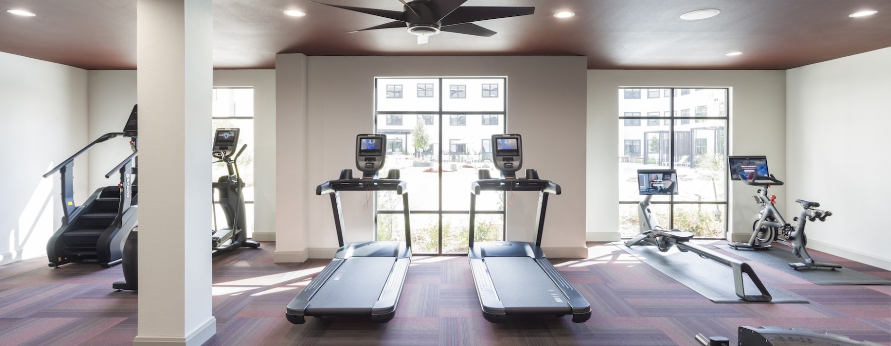 fitness center with treadmills overlooking the large pool at broadstone amelia in houston texas