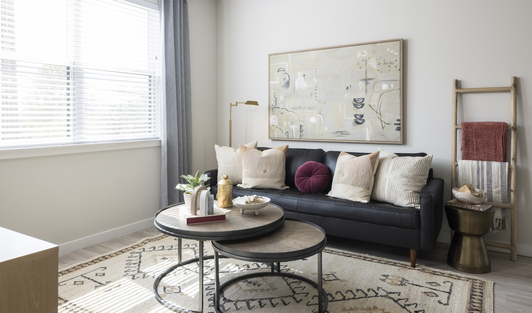 blue couch in a living room with a brown round table in front and large window with lots of light coming through at Broadstone Amelia in Houston, TX