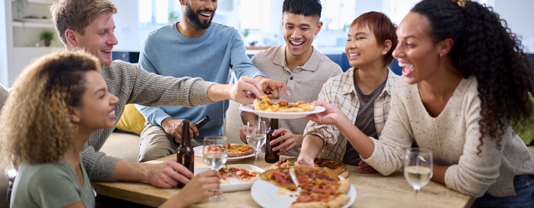 a group of people sharing pizza and drinks