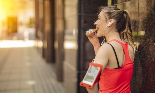 a woman outdoors with running gear on her arm